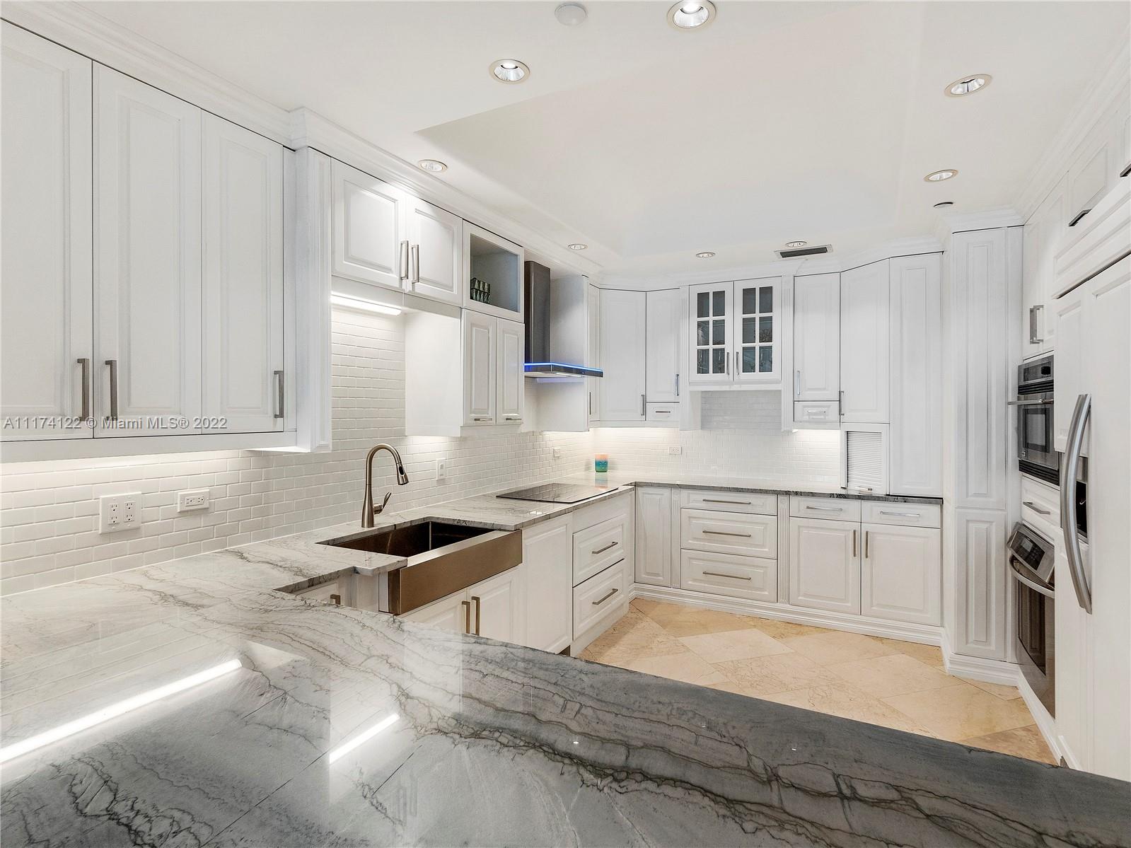 2050 Florida A1A, Unit 2 Jupiter, FL 33477 - Photo 5 of 22 a kitchen with granite countertop a sink stove refrigerator and white cabinets with wooden floor