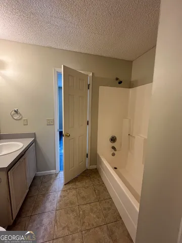 a bathroom with a tub shower sink and mirror