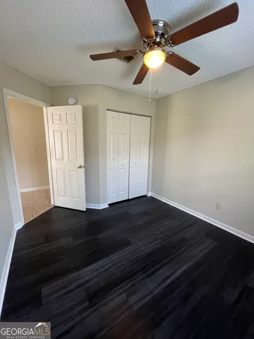 a view of empty room with wooden floor and fan