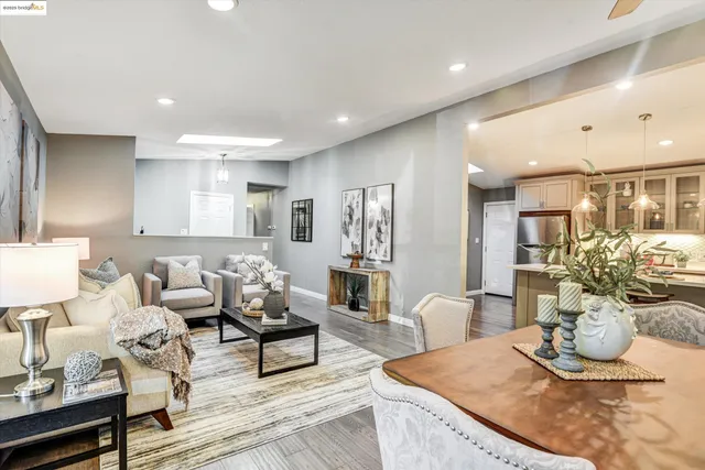 a living room with furniture kitchen view and a wooden floor