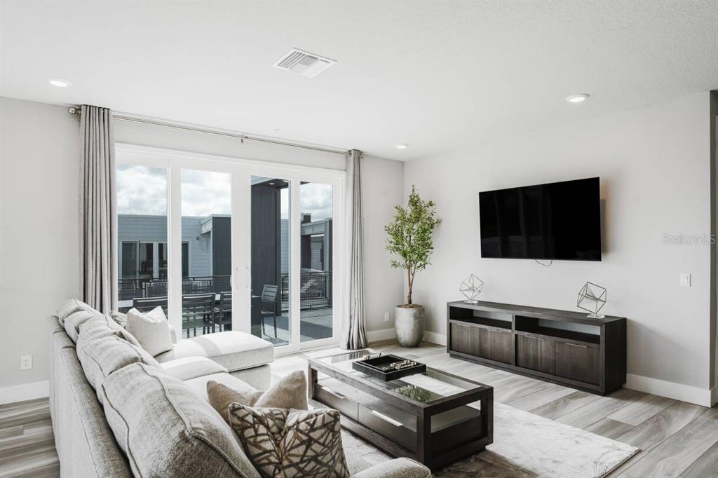 7760 Sandy Ridge Drive, Unit 226 Reunion, FL 34747 - Photo 31 of 40 a living room with furniture a flat screen tv and a floor to ceiling window