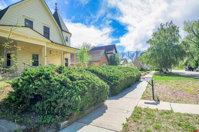 a view of a white house next to a yard