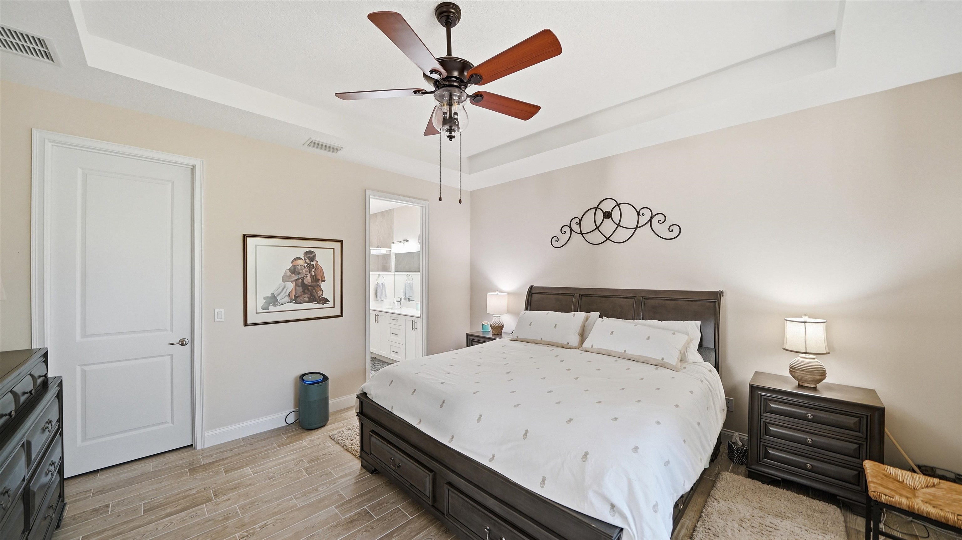 74 Wrendale Loop Ormond Beach, FL 32174 - Photo 18 of 59 Bedroom featuring a tray ceiling, wood finish floors, a ceiling fan, and ensuite bathroom