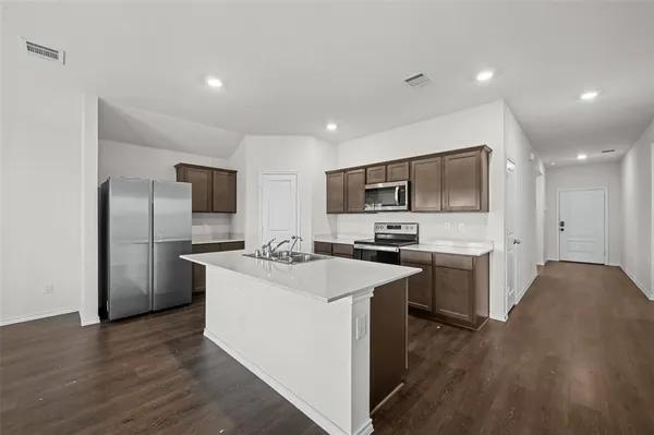 a kitchen with a sink a counter top space stainless steel appliances and cabinets