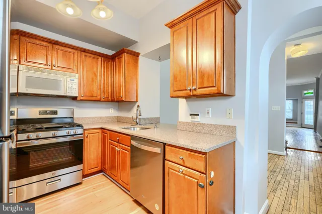 a kitchen with stainless steel appliances granite countertop wooden cabinets a stove a sink and a microwave