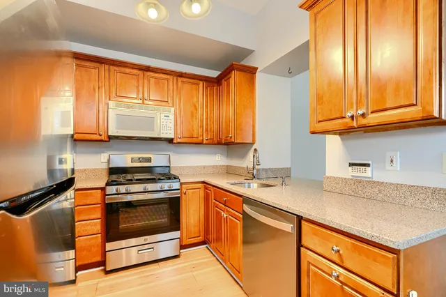 a kitchen with stainless steel appliances granite countertop wooden cabinets a stove a sink and a window
