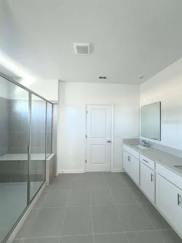 a spacious bathroom with a granite countertop sink a mirror and a bathtub