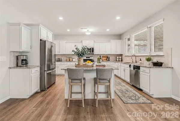 a kitchen with stainless steel appliances a refrigerator a stove a sink dishwasher with a dining table and chairs with wooden floor