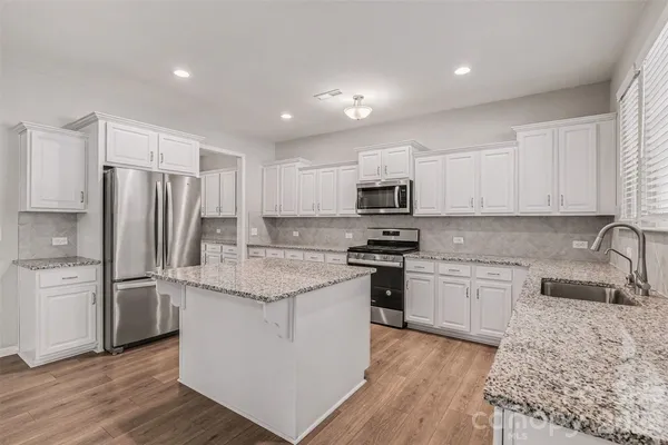 a kitchen with stainless steel appliances granite countertop a refrigerator stove microwave and sink