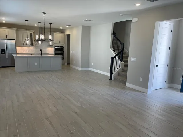 a open kitchen with kitchen island a refrigerator stove and a wooden floor