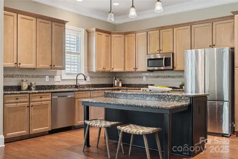 a kitchen with stainless steel appliances granite countertop a stove a refrigerator a sink a stove with white cabinets