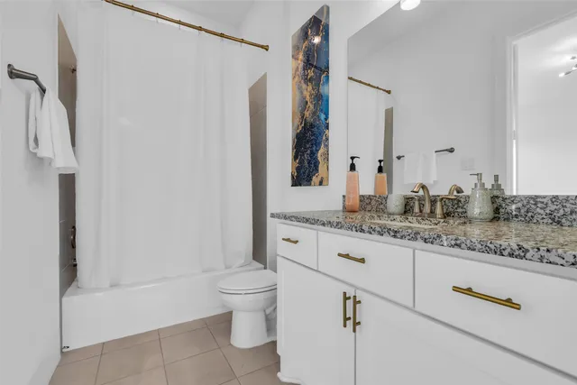 a bathroom with a granite countertop sink a toilet and a bathtub