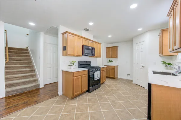 a kitchen with granite countertop a sink a stove top oven and cabinetry