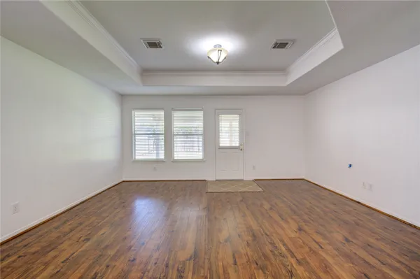 an empty room with wooden floor and windows