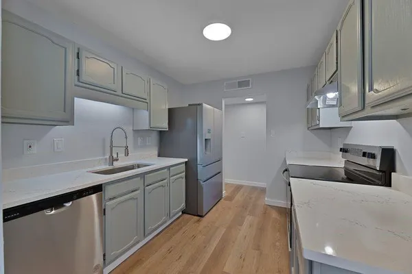 a kitchen with stainless steel appliances a sink dishwasher stove refrigerator and cabinets