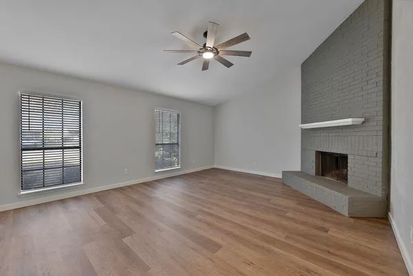 an empty room with windows and fireplace