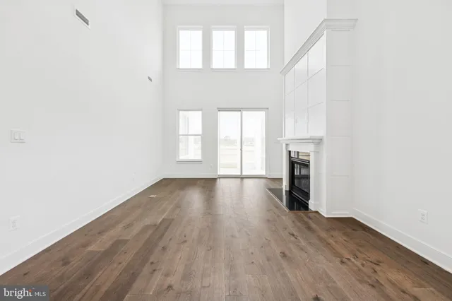 an empty room with wooden floor a fireplace and windows