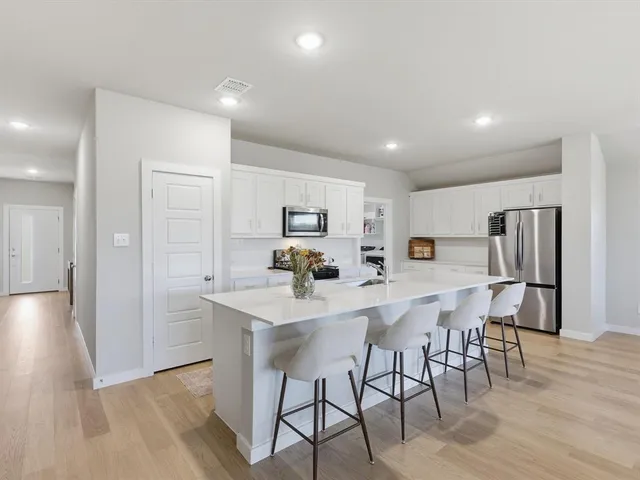 a kitchen with stainless steel appliances a table and chairs in it