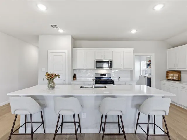 a kitchen with stainless steel appliances a sink counter space and chairs in it