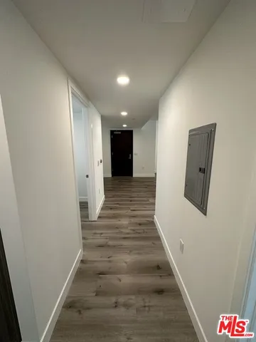 a view of an empty room with wooden floor and kitchen