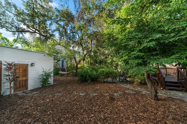 a view of a backyard with potted plants and large tree