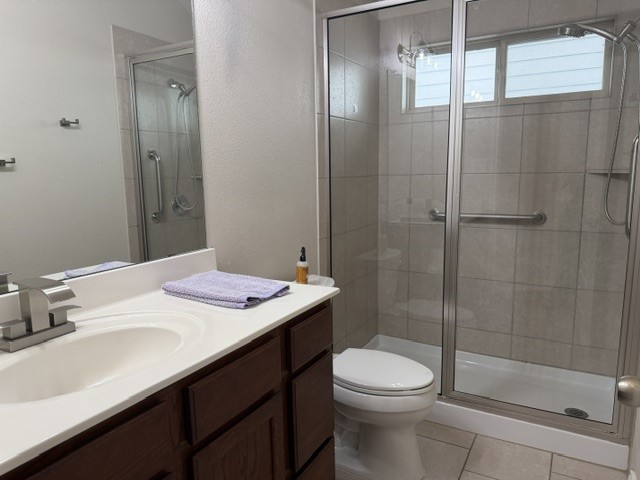 571 Dragon Ridge Road Buda, TX 78610 - Photo 12 of 16 A classic vanity sits adjacent to a glass-enclosed walk-in shower featuring tiled walls.