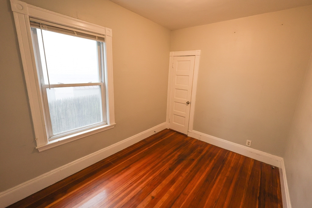 82 Fuller Street, Unit 1 Boston, MA 02124 - Photo 11 of 13 a view of an empty room with wooden floor and a window