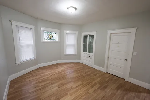 an empty room with wooden floor and windows