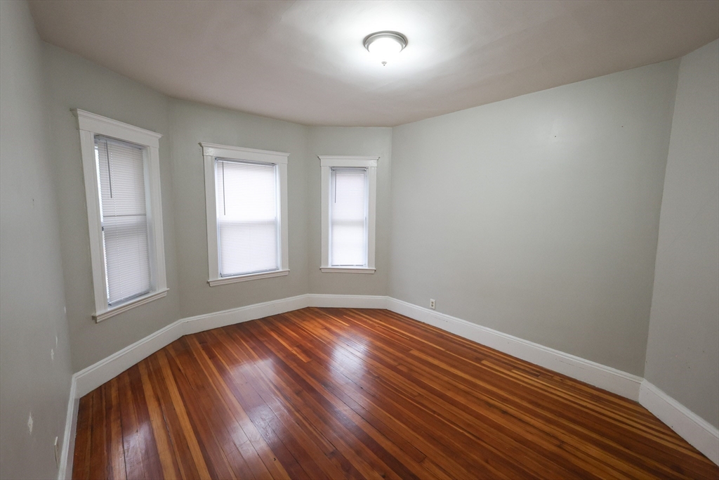 82 Fuller Street, Unit 1 Boston, MA 02124 - Photo 8 of 13 an empty room with wooden floor and windows