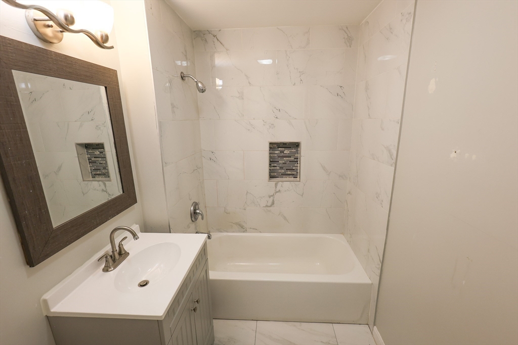 82 Fuller Street, Unit 1 Boston, MA 02124 - Photo 10 of 13 a bathroom with a bathtub a sink and a mirror