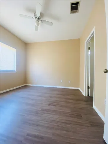 a view of an empty room with window and wooden floor