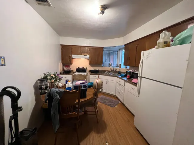 a kitchen with a refrigerator a dining table and chairs