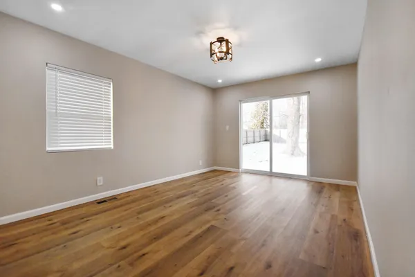 a view of an empty room with wooden floor and a window
