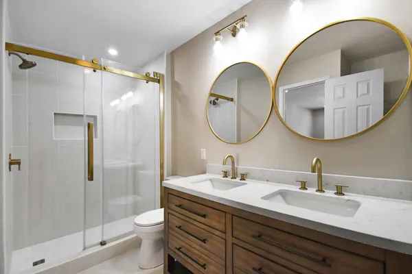 a bathroom with a double vanity sink mirror and shower
