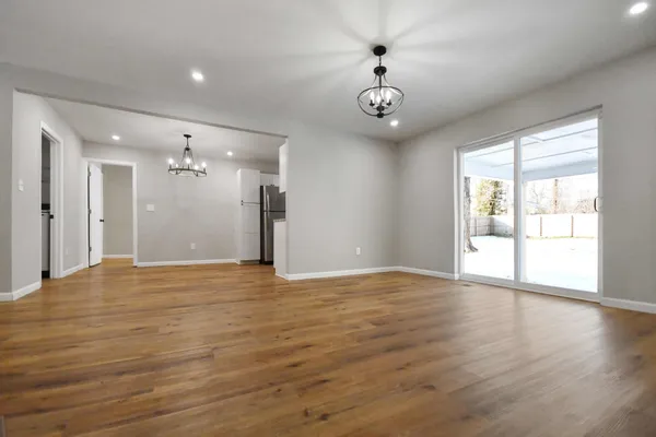 a view of an empty room with a window and wooden floor