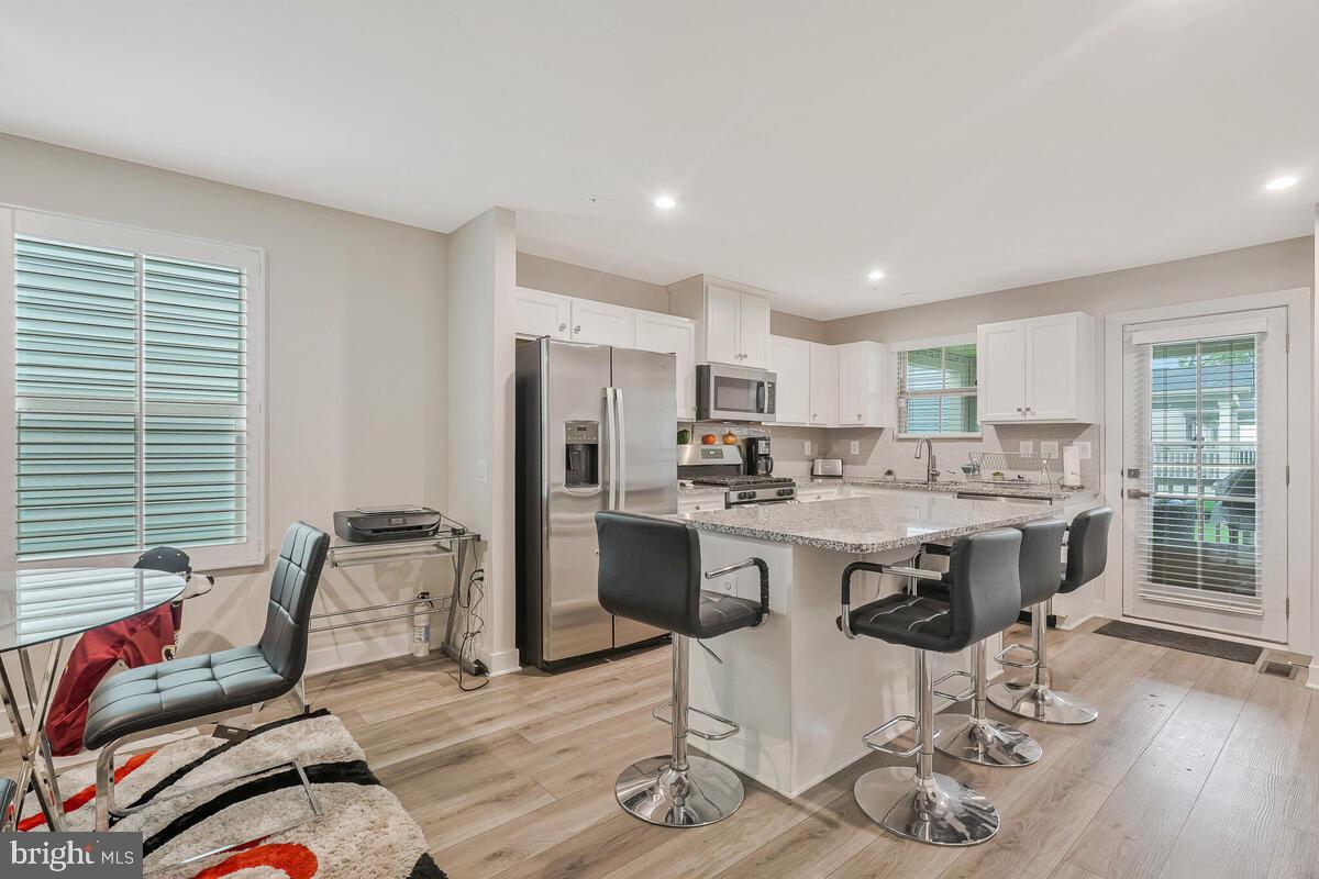 14304 Longhouse Loop, Unit A Brandywine, MD 20613 - Photo 58 of 72 a kitchen with a sink refrigerator and chairs