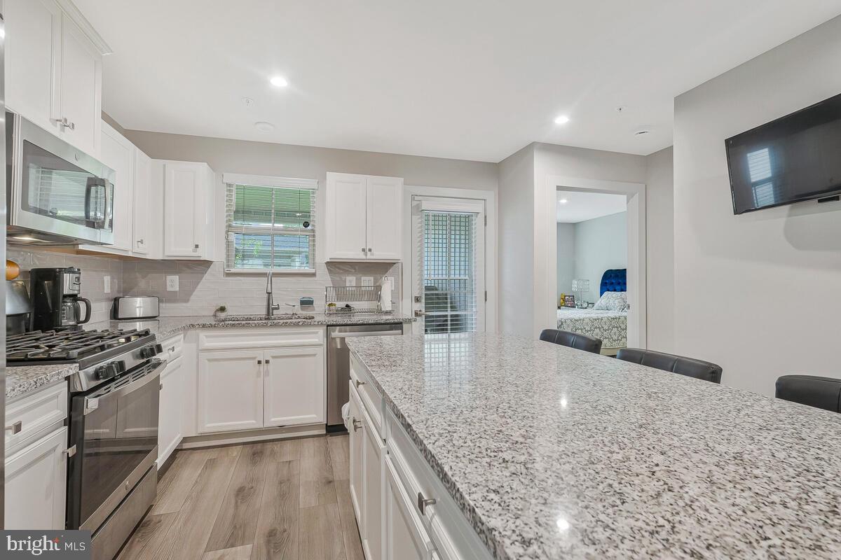 14304 Longhouse Loop, Unit A Brandywine, MD 20613 - Photo 60 of 72 a kitchen with stainless steel appliances granite countertop a stove a sink and a microwave