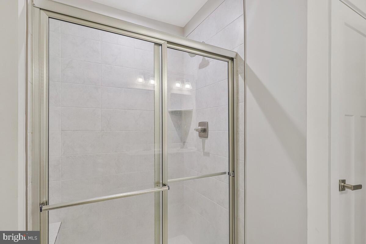 14304 Longhouse Loop, Unit A Brandywine, MD 20613 - Photo 68 of 72 a bathroom with a glass shower door