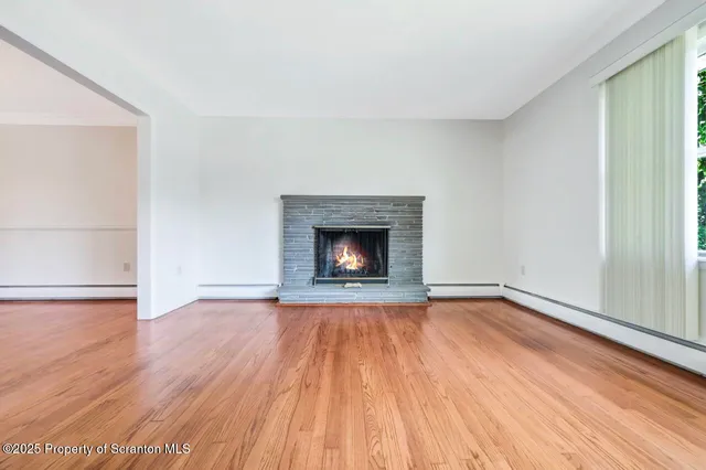 an empty room with wooden floor fire place and windows
