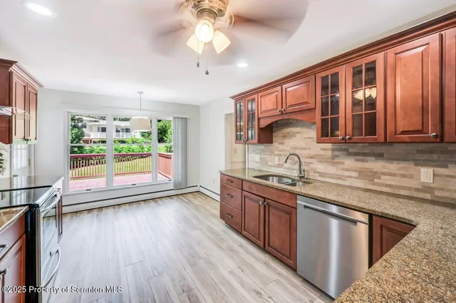 a kitchen with stainless steel appliances granite countertop a stove a sink dishwasher and a refrigerator with wooden floor