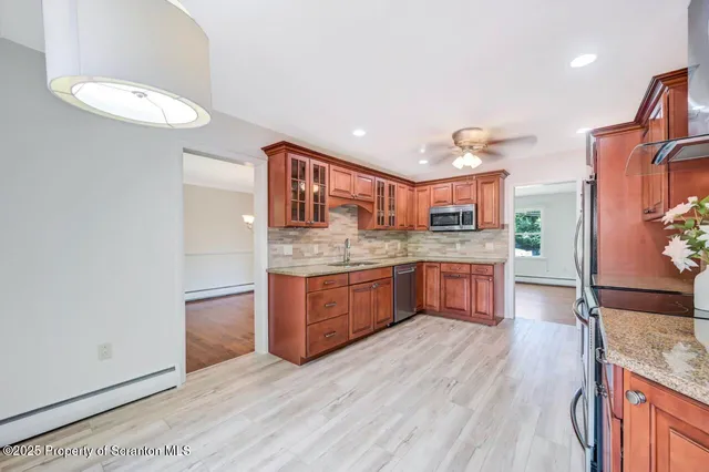 a kitchen with stainless steel appliances granite countertop a refrigerator a stove a sink and dishwasher with wooden floor