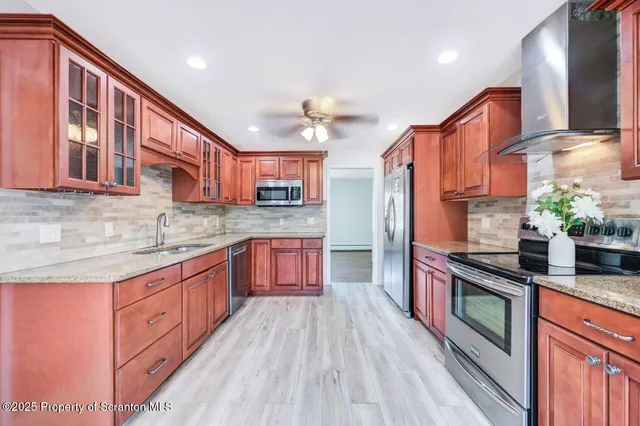 a kitchen with stainless steel appliances granite countertop a refrigerator a stove and a wooden floors