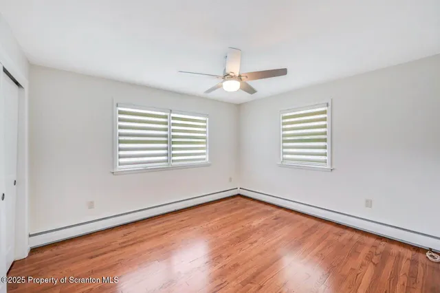 an empty room with wooden floor and a ceiling fan