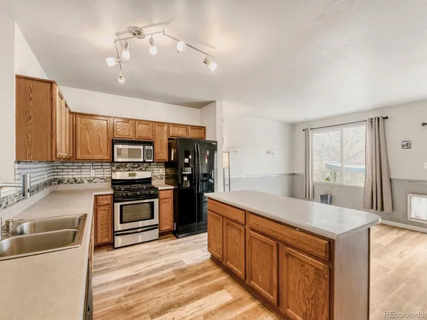 a large kitchen with stainless steel appliances granite countertop a stove refrigerator and a sink with cabinets