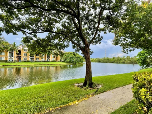 a view of a lake with a yard and large trees