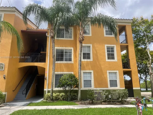 front view of house with a yard and palm trees