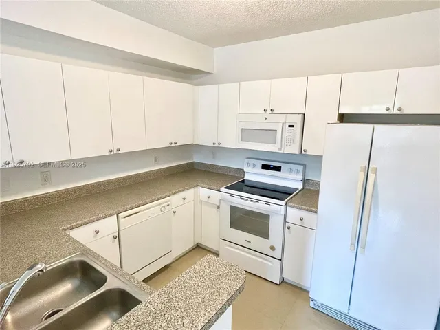 a kitchen with granite countertop white cabinets and white appliances