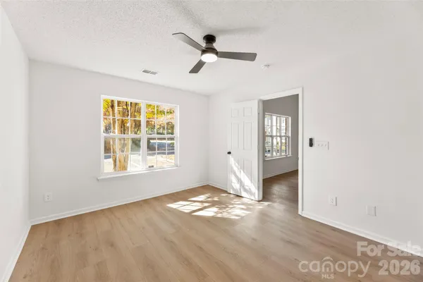 a view of empty room with wooden floor and fan