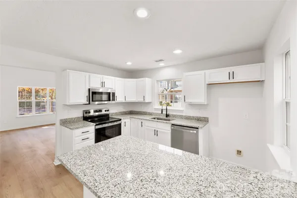 a kitchen with stainless steel appliances granite countertop a refrigerator a stove top oven a sink and dishwasher