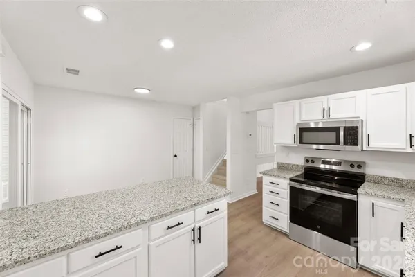 a kitchen with stainless steel appliances granite countertop a stove a sink and a microwave